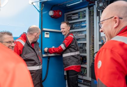 Trainer Patrick erklärt Teilnehmern die Komponenten im Schaltschrank eines Bredenoord Batteriespeichers.