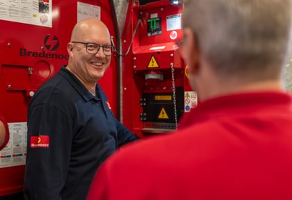 Technical Trainer Ronny spricht mit einem Teilnehmer neben dem geöffneten Bedienfeld eines Stromaggregats.
